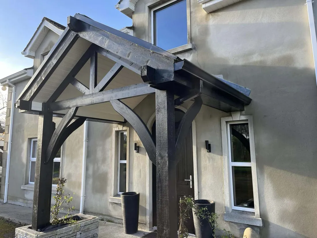 Handcrafted oak porch canopy with glass panels on a rendered house
